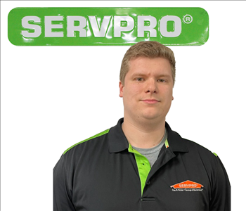Joshua, SERVPRO employee, in uniform, against a white backdrop and green SERVPRO sign